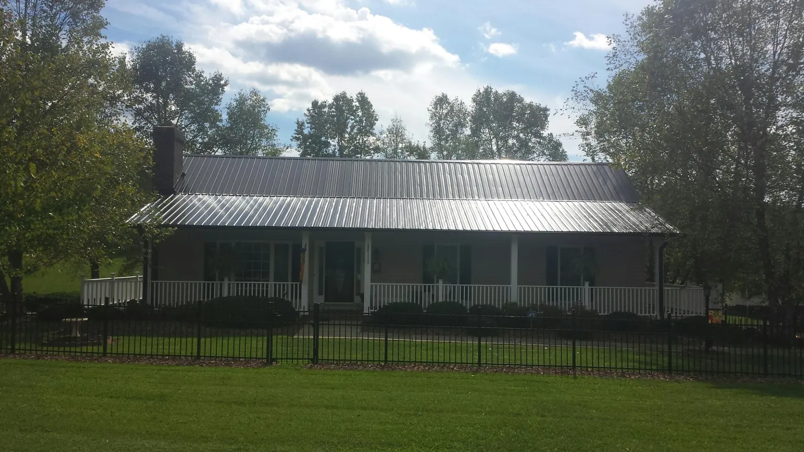 Gray metal roof on a brick ranch with a full width front porch — Gutter Guard Installation work by our crew in Lunenburg